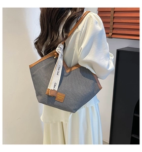 Detail of grey tote bag with brown leather straps and branded white ribbon charm