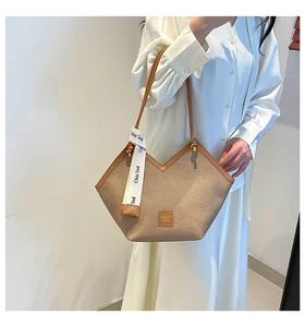 Detail of V-shaped khaki tote bag with brown leather handles and brand ribbon accent