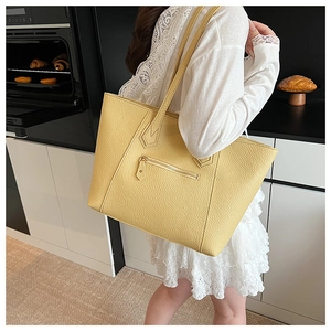 Macro detail of yellow pebble leather tote bag with functional front zipper and long straps