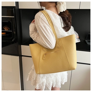 Detail of yellow pebbled leather tote bag with functional front zipper and textured finish