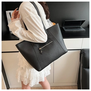 Detail of black pebbled leather tote bag with functional gold zipper and spacious interior