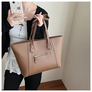 Close-up of brown litchi pattern leather tote bag showing texture and zipper detail