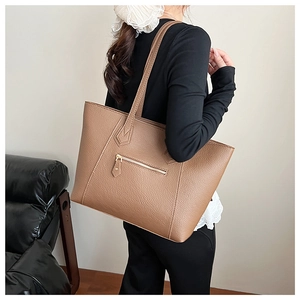 Close-up of brown litchi pattern leather tote bag with exterior zipper and double straps