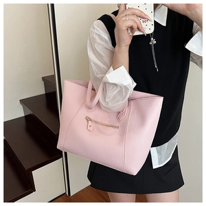 Pink pebbled leather tote bag detail with gold zipper pocket shown on a model