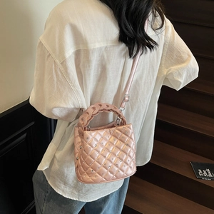 Chic pink quilted bucket bag with sparkling rhinestones and woven handle on stairs