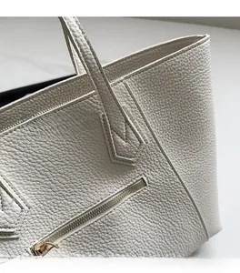 Close-up of white lychee pattern leather tote bag with precise stitching and gold zipper
