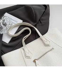 Detail of lychee pattern leather and metallic zipper on a beige tote bag
