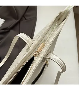 Close-up of smooth gold zipper and white lychee texture on large tote bag