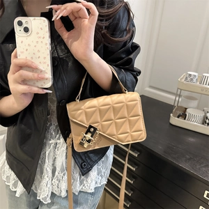 Quilted camel crossbody bag with gold lock and chain handle worn by a model