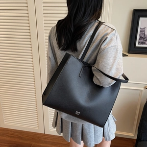 Borsa tote retrò in pelle nera con logo MER PAI, indossata in un ambiente minimalista