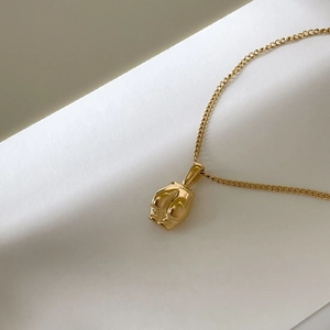Détail macro du collier en titane doré avec pendentif aux formes fluides et bio