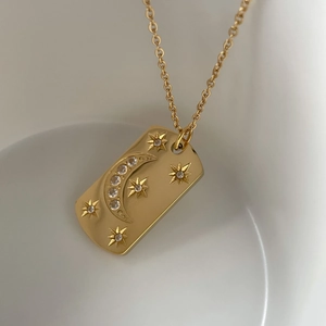 Vue macro d'un pendentif rectangulaire doré avec lune et étoiles serti de zircons
