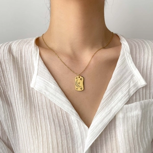 Gros plan du collier pendentif rectangulaire lune et étoile sur un chemisier blanc