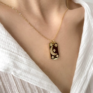 Détail d'un collier pendentif vintage lune et étoile dorées sur une chemise blanche