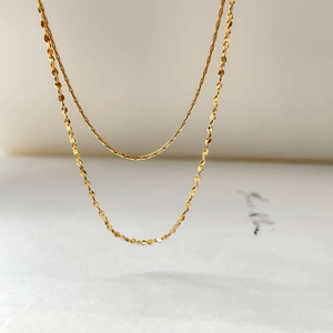 Detail of double-layered gold snake chain and shimmering sequin necklace for women