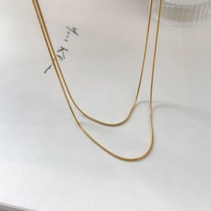Detail of minimalist double-layered gold snake chain necklace with smooth metal texture