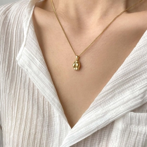 Gros plan d'un collier vintage doré avec un pendentif poli en forme de dent unique