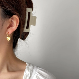 Close-up of elegant gold heart earrings with textured finish worn by a model