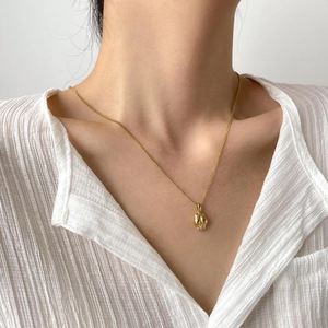 Détail d'un collier vintage doré lune et étoile porté sur une chemise blanche