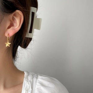 Elegant gold star pendant earrings and cream rectangle hair claw clip on model