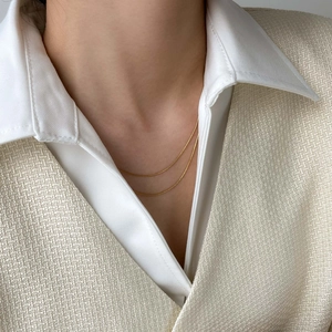 Close-up of a double layer gold snake chain necklace worn on a woman's collarbone