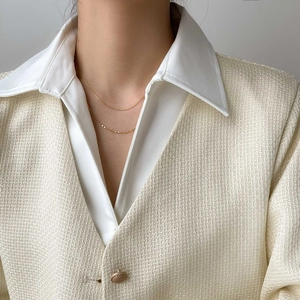 Close-up of double layered gold snake chain necklace on a model wearing a tweed jacket