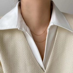 Close-up of double-layered gold snake chain necklace worn with a white shirt