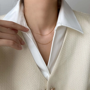 Close-up of a double-layered gold snake chain necklace worn with a white elegant shirt