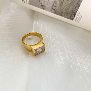 Close-up of gold titanium steel ring with rectangular zircon on white organza silk