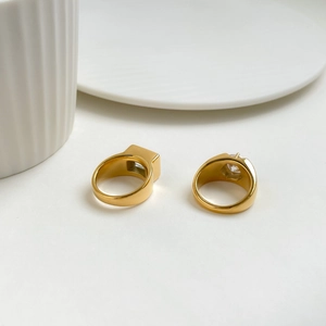 Detail of gold titanium steel rings with square and round cubic zirconia stones