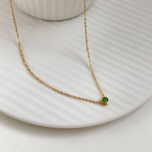 Elegante collana d'oro con un ciondolo minimalista con gemma verde rotonda su catena fine