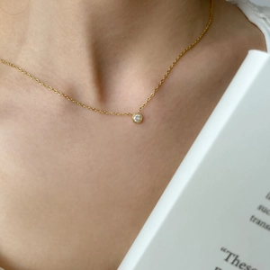 Dettaglio della collana d'oro minimalista con ciondolo a cerchio sul décolleté