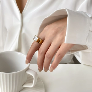 Close-up of a wide gold-plated titanium ring featuring a large rectangular zircon stone