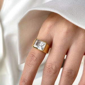 Close-up of gold titanium steel ring with a large emerald-cut zircon on model hand
