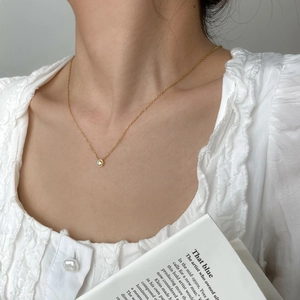 Dettaglio della collana dorata con ciondolo a cristallo rotondo indossata da una modella