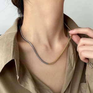 Gros plan détaillé d'un collier chaîne serpent bicolore or et argent sur un mannequin