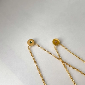 Dettaglio macro di delicate collane d'oro con piccole pietre preziose tonde verdi e chiare