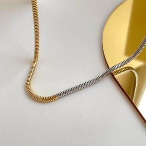 Détail de la chaîne serpent bicolore dorée et argentée avec reflet sur miroir