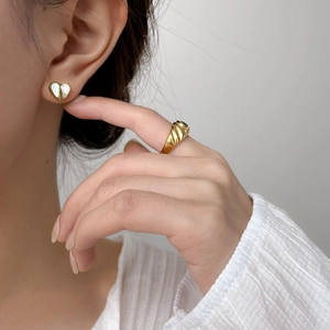 Eleganti orecchini a cuore dorati con inserto in conchiglia bianca indossati da modella