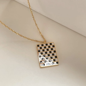 Detail of golden checkered pendant with black and white grid on a twisted chain