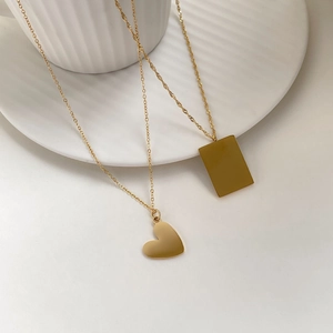 Close-up of minimalist gold heart and rectangle pendant necklaces on a white tray