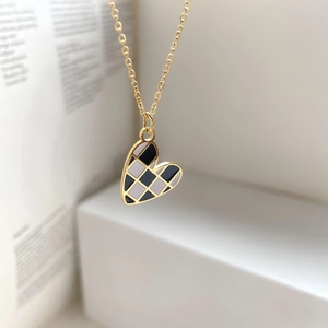 Macro view of a gold heart pendant with black and white checkerboard enamel pattern
