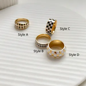 Macro detail of four gold checkerboard and diamond pattern rings on ceramic tray