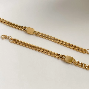 Detail of the golden Cuban link chain featuring rectangular metal accents and a lobster clasp