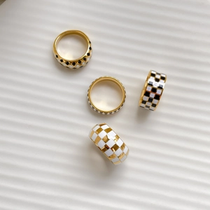 Set of four minimalist gold-plated rings with black and white checkerboard enamel patterns