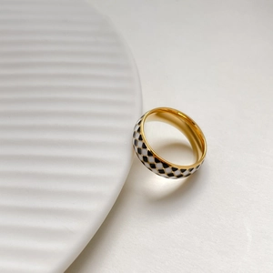 Detailed close-up of wide gold checkered ring with black and white enamel finish