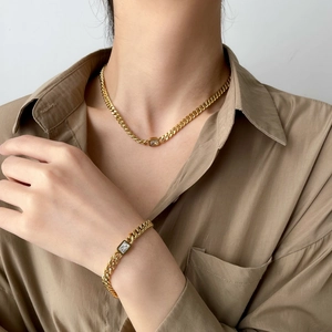 Macro detail of gold curb chain jewelry set featuring emerald-cut clear cubic zirconia