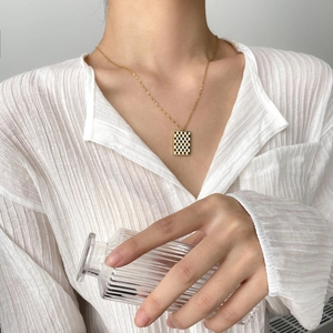 Golden rope chain necklace with a black and white checkerboard rectangle pendant