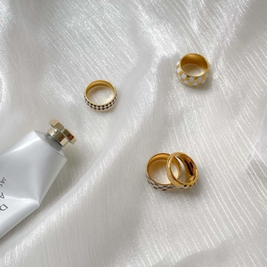Detailed shot of gold-plated checkerboard rings on white wrinkled silk fabric