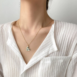 Gold-tone checkerboard heart necklace displayed on a model with minimalist style